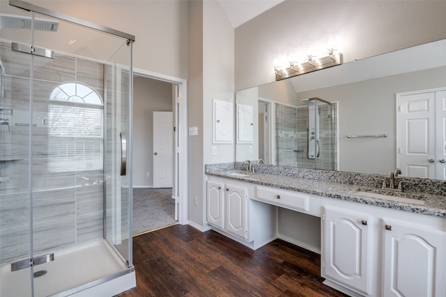 bathroom featuring vanity, hardwood / wood-style floors, vaulted ceiling, and a shower with shower door