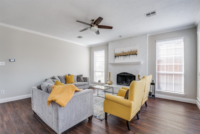 living room with a textured ceiling, dark hardwood / wood-style floors, ceiling fan, and a brick fireplace