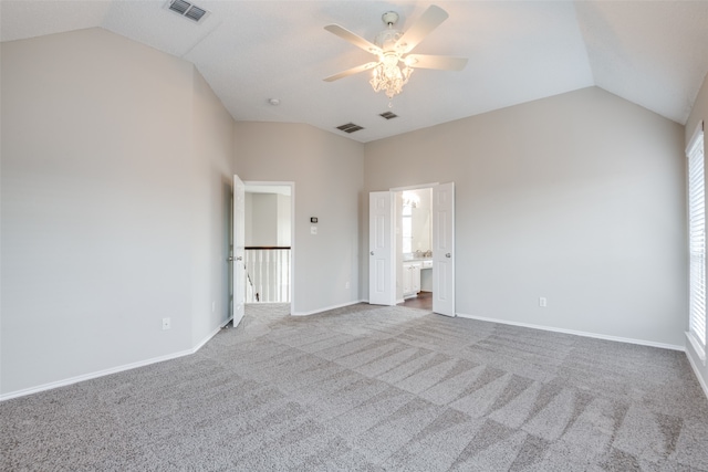 unfurnished bedroom with ceiling fan, carpet flooring, connected bathroom, and vaulted ceiling