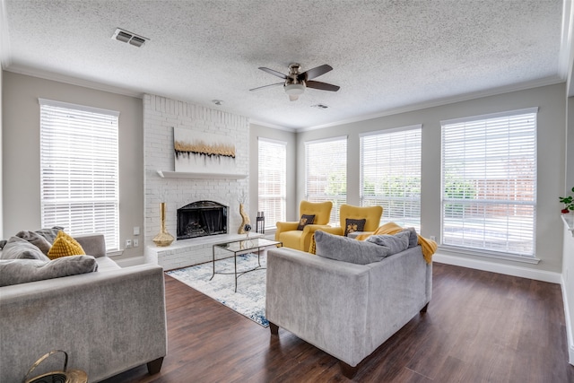 living room with a brick fireplace, crown molding, dark hardwood / wood-style flooring, and ceiling fan