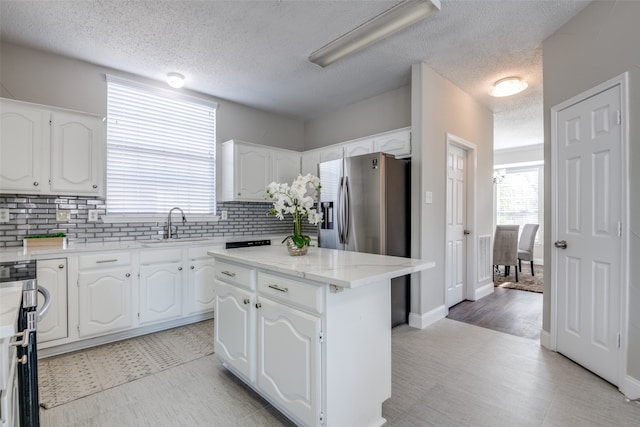 kitchen with decorative backsplash, white cabinets, a center island, and stainless steel fridge with ice dispenser