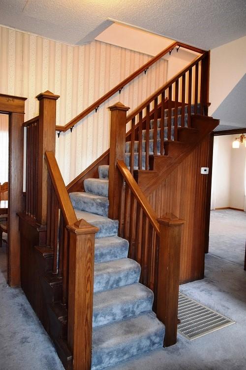 stairway with a textured ceiling, carpet, and wallpapered walls