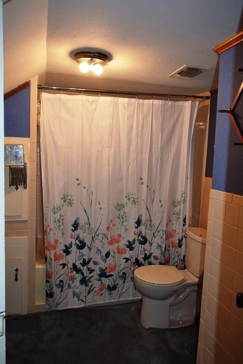 full bath with tile walls, toilet, shower / bath combo, and visible vents