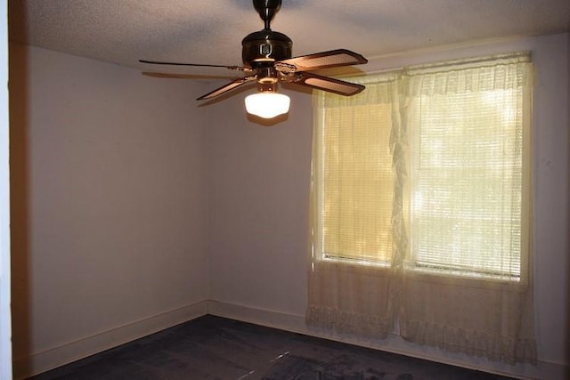 empty room with baseboards, a textured ceiling, and dark wood-style flooring