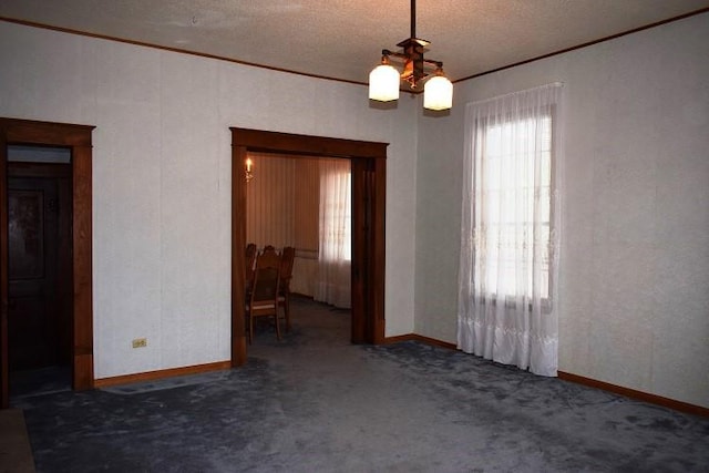 carpeted empty room featuring a textured ceiling, an inviting chandelier, and crown molding