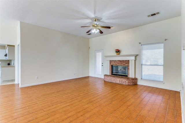 unfurnished living room featuring ceiling fan, light hardwood / wood-style flooring, and a brick fireplace