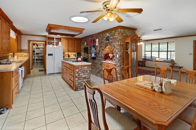 kitchen with light tile patterned flooring, white appliances, ornamental molding, and brick wall