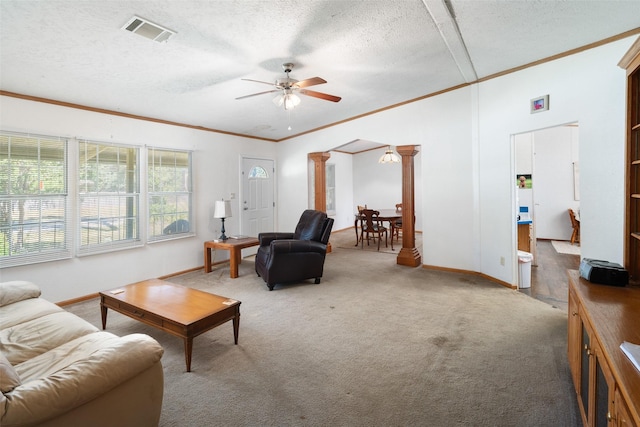 carpeted living room with ceiling fan, ornamental molding, a textured ceiling, and ornate columns