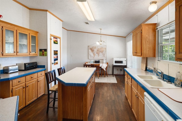 kitchen with sink, white appliances, a center island, ornamental molding, and decorative light fixtures