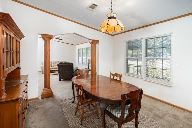 dining room featuring light colored carpet, ornamental molding, decorative columns, and a textured ceiling