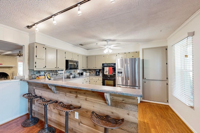 kitchen featuring kitchen peninsula, black appliances, ceiling fan, light hardwood / wood-style flooring, and ornamental molding