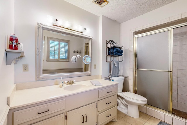 bathroom with vanity, tile patterned flooring, a textured ceiling, a shower with shower door, and toilet