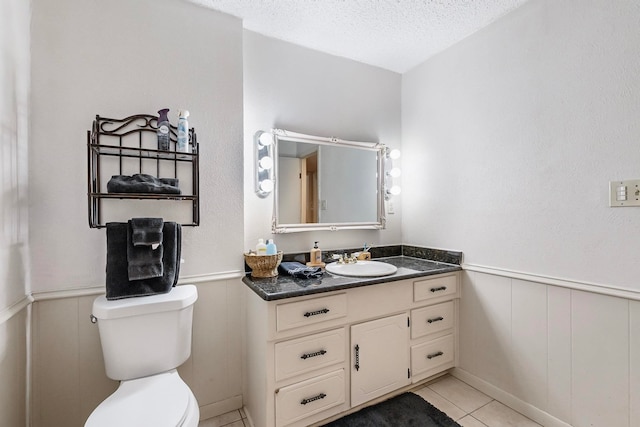 bathroom featuring tile patterned flooring, a textured ceiling, vanity, and toilet