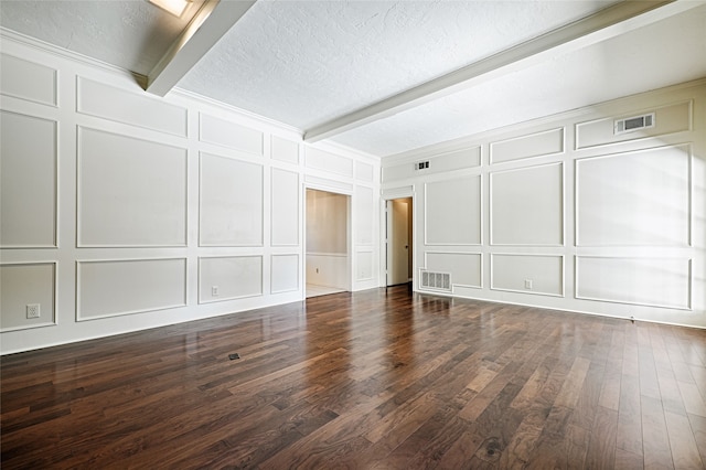 spare room featuring a textured ceiling, beam ceiling, and dark wood-type flooring