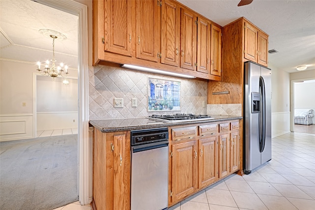 kitchen with ceiling fan with notable chandelier, stainless steel appliances, backsplash, and light tile patterned floors