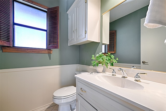 bathroom with toilet, vanity, and tile patterned flooring