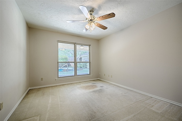 carpeted spare room featuring a textured ceiling and ceiling fan