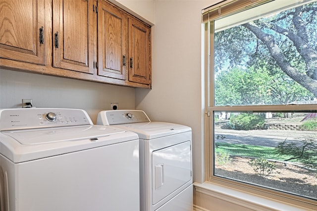 clothes washing area with cabinets and separate washer and dryer