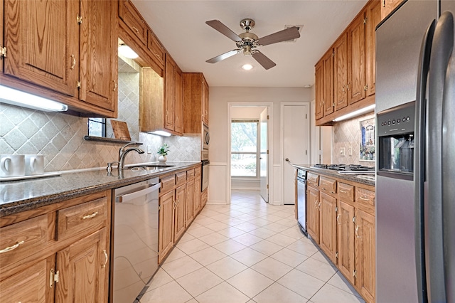 kitchen featuring stainless steel appliances, backsplash, sink, light tile patterned floors, and ceiling fan