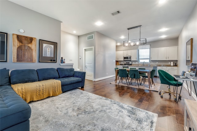 living room featuring a chandelier, sink, and dark hardwood / wood-style flooring