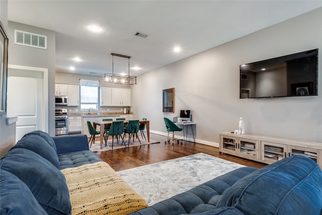 living room featuring dark hardwood / wood-style floors, sink, and a notable chandelier