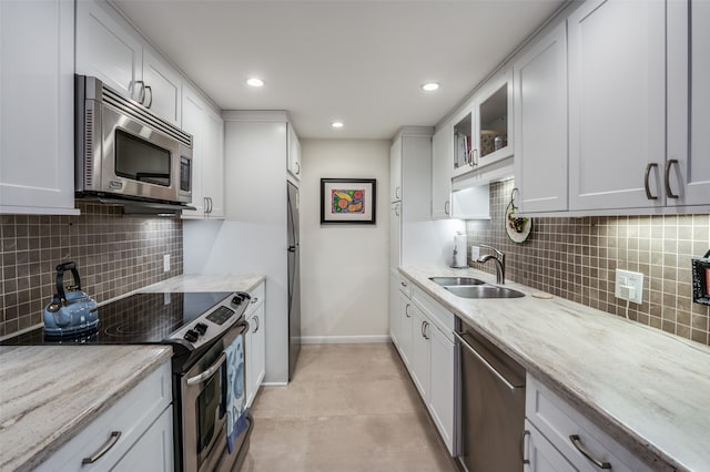 kitchen with white cabinets, stainless steel appliances, backsplash, and light stone countertops