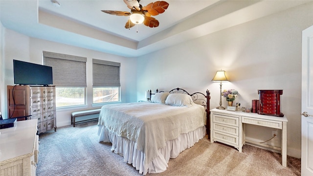 bedroom featuring ceiling fan, carpet floors, and a tray ceiling