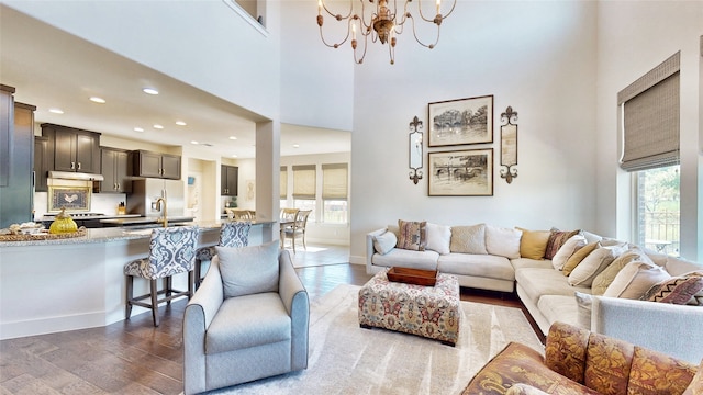 living room featuring an inviting chandelier, sink, dark hardwood / wood-style flooring, and a healthy amount of sunlight