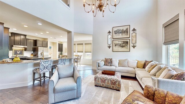 living room with a notable chandelier, a fireplace, a towering ceiling, and hardwood / wood-style floors