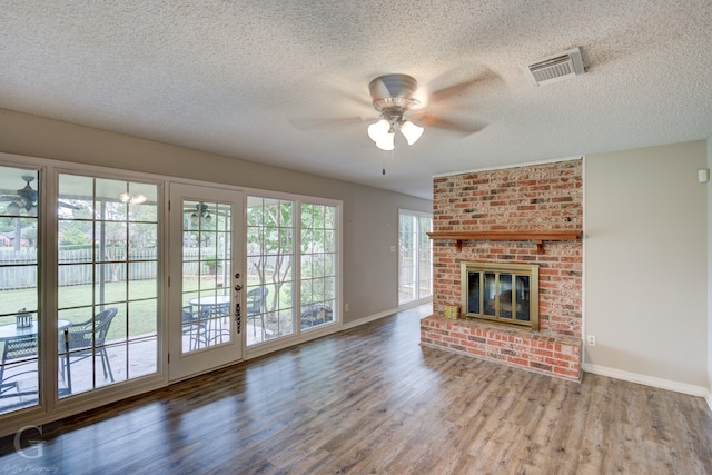 unfurnished living room with ceiling fan, a textured ceiling, a brick fireplace, and wood-type flooring