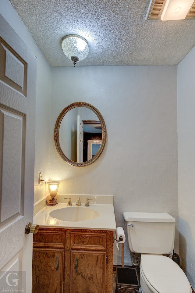 bathroom with a textured ceiling, vanity, and toilet