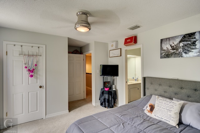 carpeted bedroom featuring a closet, ceiling fan, ensuite bathroom, and a textured ceiling