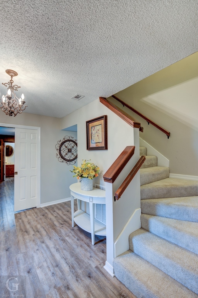 stairway featuring a chandelier, a textured ceiling, and hardwood / wood-style flooring