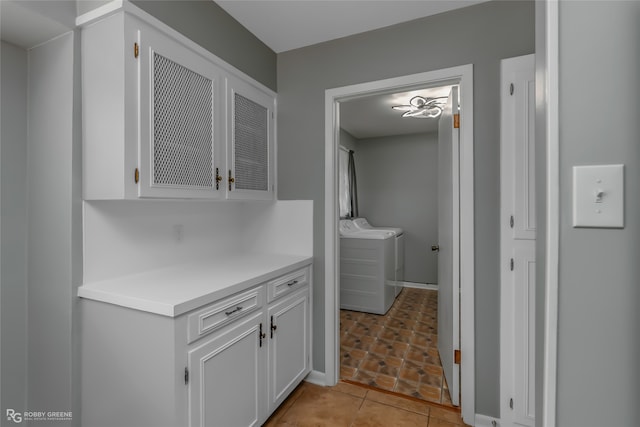 interior space with white cabinets, light tile patterned flooring, and washing machine and clothes dryer