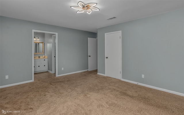 unfurnished bedroom with light carpet and connected bathroom