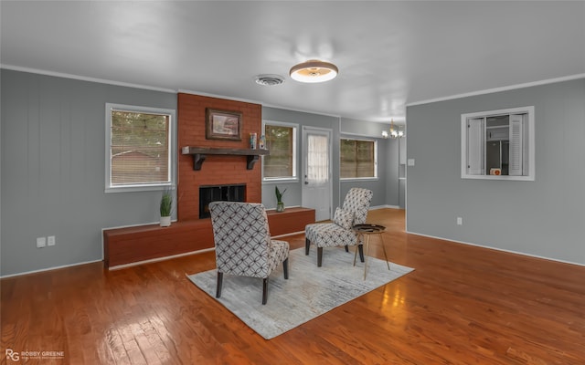 interior space with a notable chandelier, a brick fireplace, wood-type flooring, and crown molding