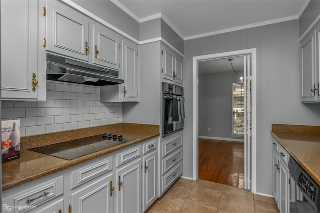 kitchen with dark stone countertops, light wood-type flooring, ornamental molding, and black appliances