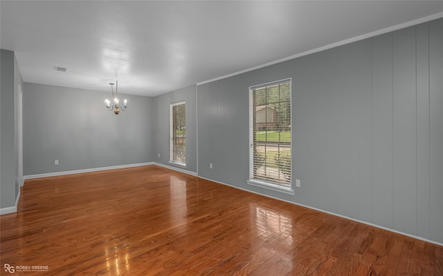 unfurnished room featuring crown molding, hardwood / wood-style floors, and a notable chandelier