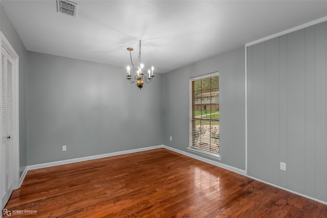 spare room featuring an inviting chandelier and hardwood / wood-style floors