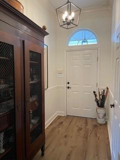 foyer entrance with a chandelier, crown molding, and wood-type flooring