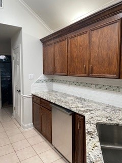 kitchen featuring light stone countertops, light tile patterned flooring, vaulted ceiling, and ornamental molding