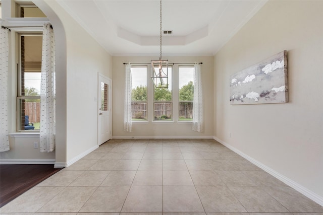 unfurnished dining area featuring crown molding, light tile patterned floors, and a raised ceiling