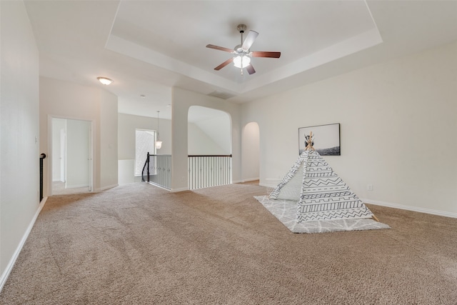 recreation room featuring ceiling fan, light colored carpet, and a raised ceiling