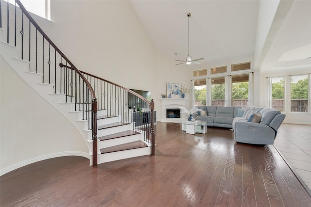 living room with ceiling fan, a towering ceiling, and hardwood / wood-style floors