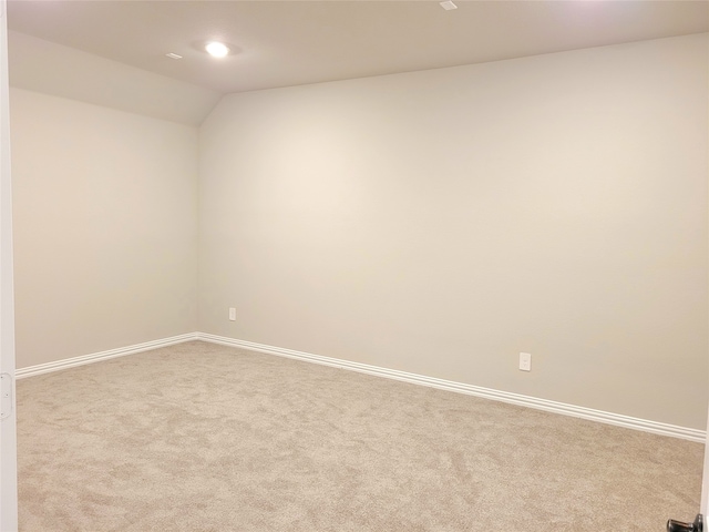 carpeted empty room with lofted ceiling