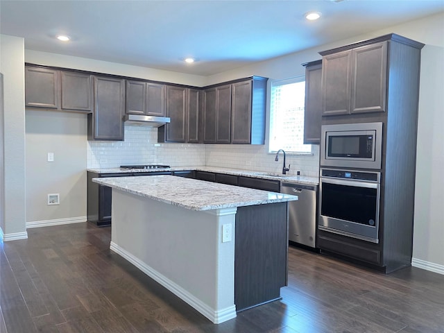 1516 Fairweather Way, Forney, TX 75126 - kitchen featuring appliances with stainless steel finishes, under cabinet range hood, a center island, dark brown cabinets, and dark wood-style floors