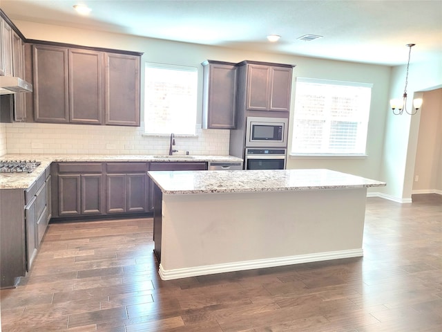 kitchen featuring light stone countertops, appliances with stainless steel finishes, sink, and pendant lighting