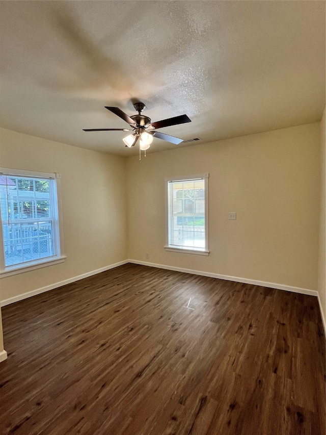 empty room with a textured ceiling, dark hardwood / wood-style floors, and ceiling fan