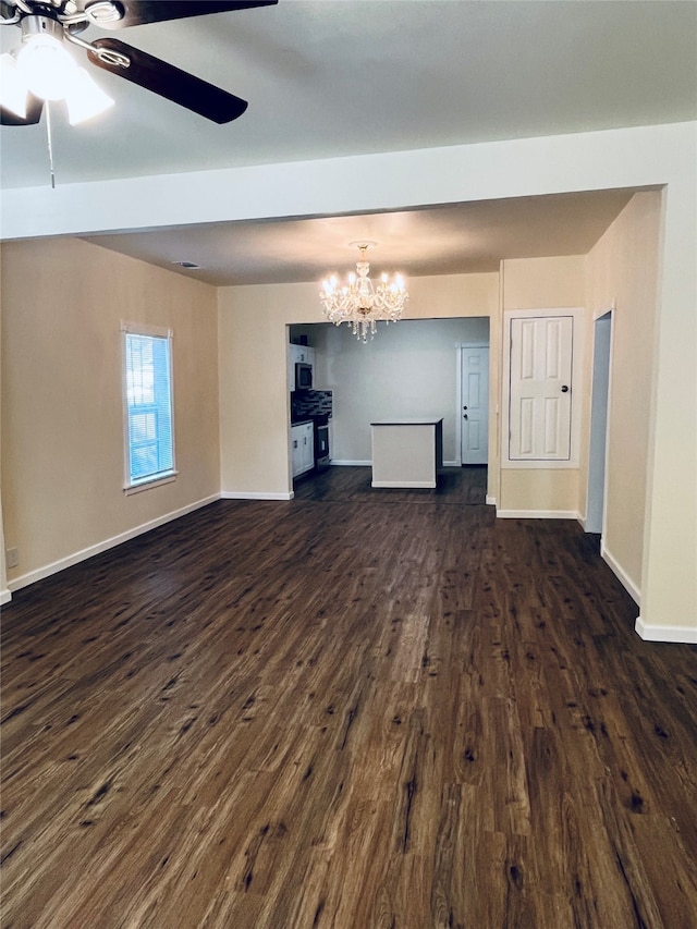 unfurnished living room with ceiling fan with notable chandelier and dark wood-type flooring