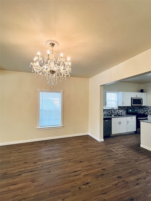 interior space featuring white cabinets, stainless steel appliances, decorative light fixtures, dark hardwood / wood-style floors, and a chandelier